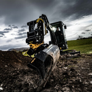 Black excavator with engcon tiltrotator and bucket attached.