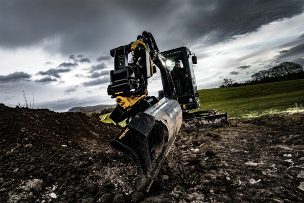 Black excavator with engcon tiltrotator and bucket attached.