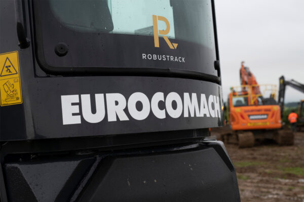 Black excavator rear window with Robustrack logo sticker above Eurocomach sticker.