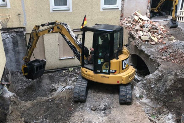 CAT digger with C50 crusher bucket working in a back garden